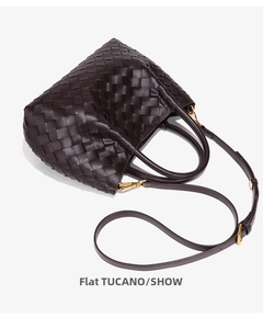 Detailed macro view of woven leather texture and gold-tone strap buckle on bucket bag