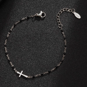 Detail of stainless steel beaded cross bracelet on a premium black textured surface
