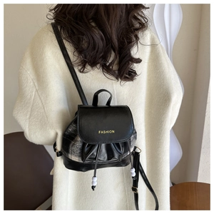 Detail eines Mini-Rucksacks mit Karomuster, schwarzem Leder und Fashion-Schriftzug