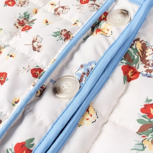 Detail of floral quilted cotton jacket with contrast blue binding and white buttons