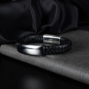 Dettaglio di un bracciale da uomo in pelle nera intrecciata con chiusura magnetica argento