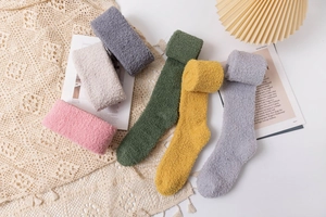 Thick coral fleece over-knee socks in various warm colors displayed on a cozy knit blanket