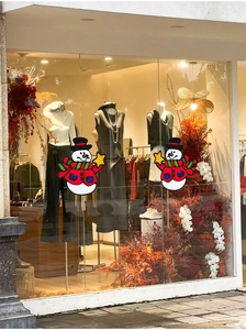 Détail de stickers bonhomme de neige colorés sur vitre avec fond de magasin festif