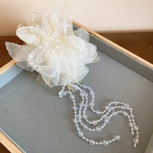 Details einer Organza-Blumen-Haarklammer mit schillernden Perlen auf grauem Samt