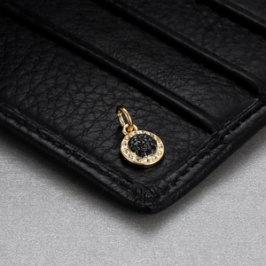 Detailed shot of a gold round pendant with black rhinestones on dark leather background