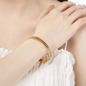 Detail of 18K gold-plated titanium bangle with double-row diamond pavé and textured edges