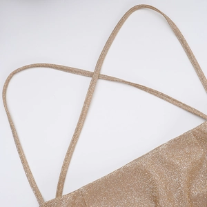 Close-up of champagne gold glitter fabric and delicate criss-cross straps detail