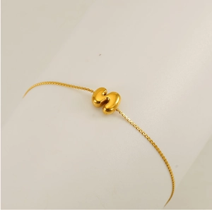 Close-up of a delicate gold chain bracelet featuring a 3D bubble letter pendant