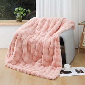 Detailed texture of pink faux rabbit fur blanket draped over a grey armchair in a cozy room