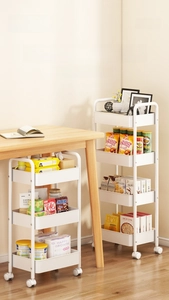 Detail of multi-layer white metal utility cart with swivel wheels under a desk