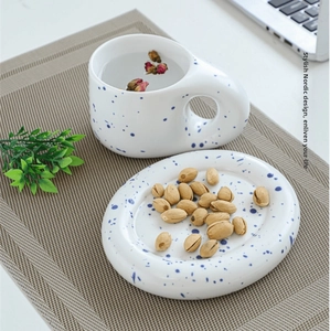 Ceramic coffee cup set with blue splatter pattern on an oval saucer and big handle