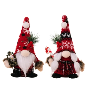 Christmas gnome dolls with knitted hats holding vintage oil lamp and candy cane on white background