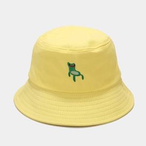 Macro detail of cute green frog embroidery on vibrant yellow cotton bucket hat surface