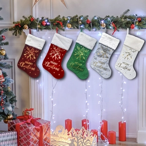 Five velvet Christmas stockings with white fur trim hanging on a festive decorated fireplace