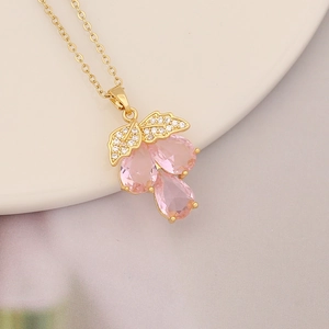 Close-up of a gold grape pendant necklace with pink stones and sparkling crystals