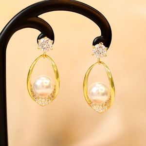 Detail shot of long tassel pearl earrings with gold hollow frames and cubic zirconia