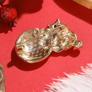 Creative Christmas snowman brooch in gold alloy with diamonds on festive red background