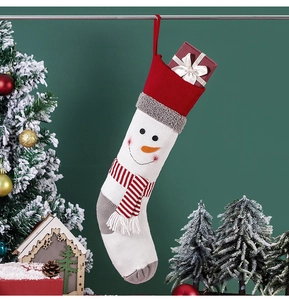 Detail of white knitted Christmas stocking featuring a snowman with red scarf and hat