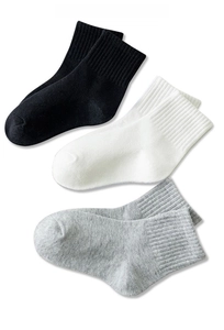 Detailed knit texture of white, black, and grey mid-calf cotton socks with ribbed cuffs