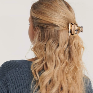Medium tortoise shell acetate hair claw clip shown on a model's wavy half-up hairstyle