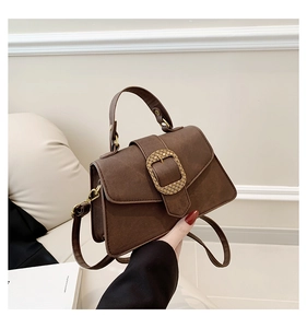 Close-up of vintage brown matte leather handbag with textured gold buckle and handle