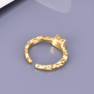 Adjustable golden stainless steel ring with unique irregular hammered texture on grey background