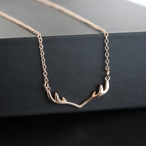 Macro close-up of a delicate golden reindeer antler pendant necklace on a dark surface