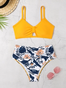 Detail von orangefarbenem Bikinioberteil mit Knoten und tropisch gemusterter High-Waist-Hose