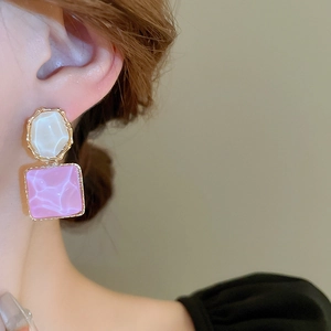Nahaufnahme der geometrischen Marmorohrringe mit Goldrand und rosa Harzstruktur