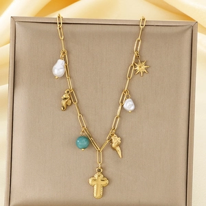 Detail of gold necklace with sea charms, starfish, cross, shell and pearl on silk fabric