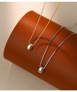 Macro view of gold and silver bean pendants on fine box chains over leather