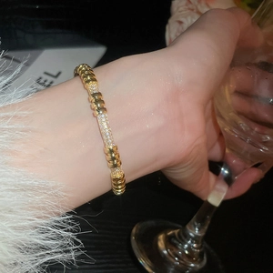 Macro shot of 18K gold plated bangle featuring sparkling zircon pave settings and studs