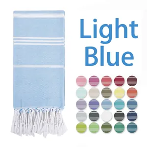 Detail of light blue striped Turkish towel with fringe and colorful fabric swatches