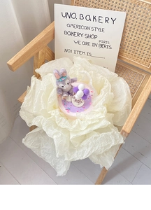 Close-up of StellaLou plush toy on creamy white crepe paper flower base decoration