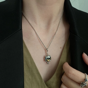 Minimalist silver cat and fish pendant necklace on model wearing black blazer