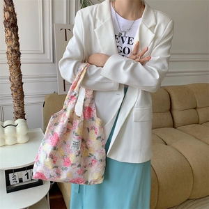 Dettaglio della borsa tote in tela a fiori indossata con un blazer bianco elegante