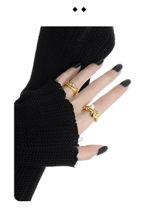 Detail of gold textured rings with zircon and pearl on model hand with black sleeves