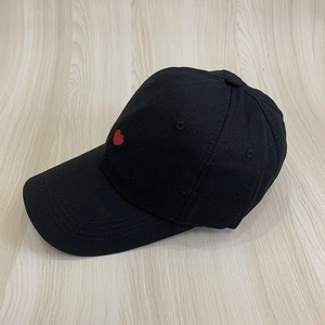 Classic black cotton baseball cap featuring a red heart embroidery on light wood background