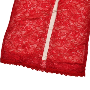 Close-up detail of red floral lace fabric and wavy scalloped hemline on the garment