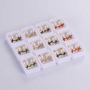 Detailed set of golden cross stud earrings with colorful rhinestones in plastic boxes
