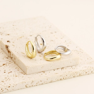 Close-up of S925 hallmark on irregular geometric gold and silver hoop earrings