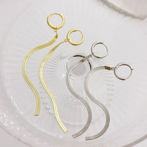 Minimalist gold and silver snake chain tassel earrings on a decorative glass tray