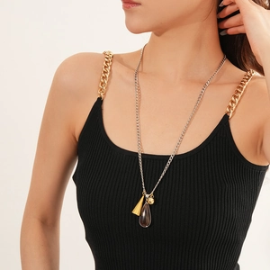 Close-up of bicolor necklace with brown teardrop gemstone and gold cone pendant