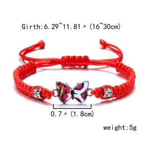Macro detail of red woven bracelet with butterfly charm and silver rhinestone beads