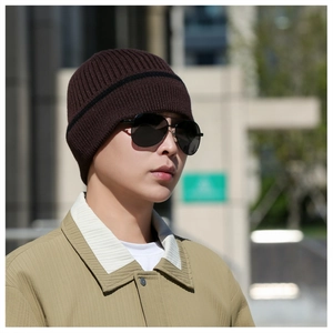Outdoor street view of a male model wearing a dark coffee ribbed knit beanie for winter