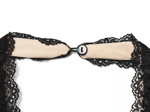 Détail d'une robe en dentelle noire avec fermeture éclair au cou et doublure beige