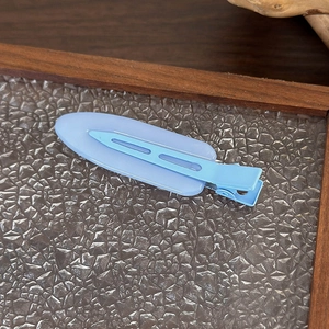 Dettaglio di un fermaglio per capelli ovale blu opaco su superficie strutturata