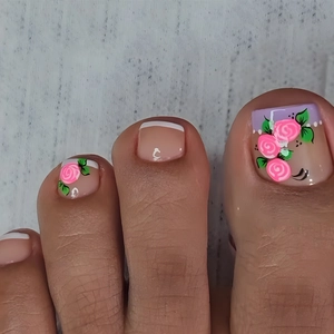 Macro shot of French toe nails featuring pink rose patterns and white tips on nude base