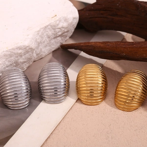 Detailed view of gold and silver oval stud earrings with elegant horizontal textured stripes