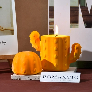 Close-up of orange cactus shaped scented candle with detailed texture and warm flame